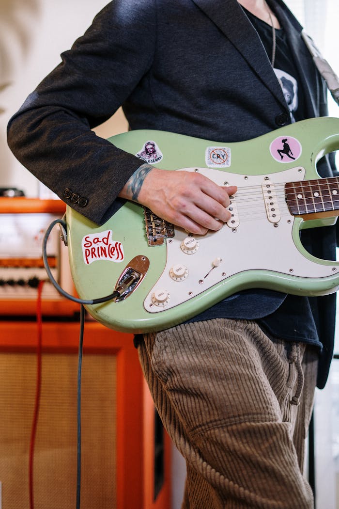 Man in Black Jacket Playing White and Red Stratocaster Electric Guitar